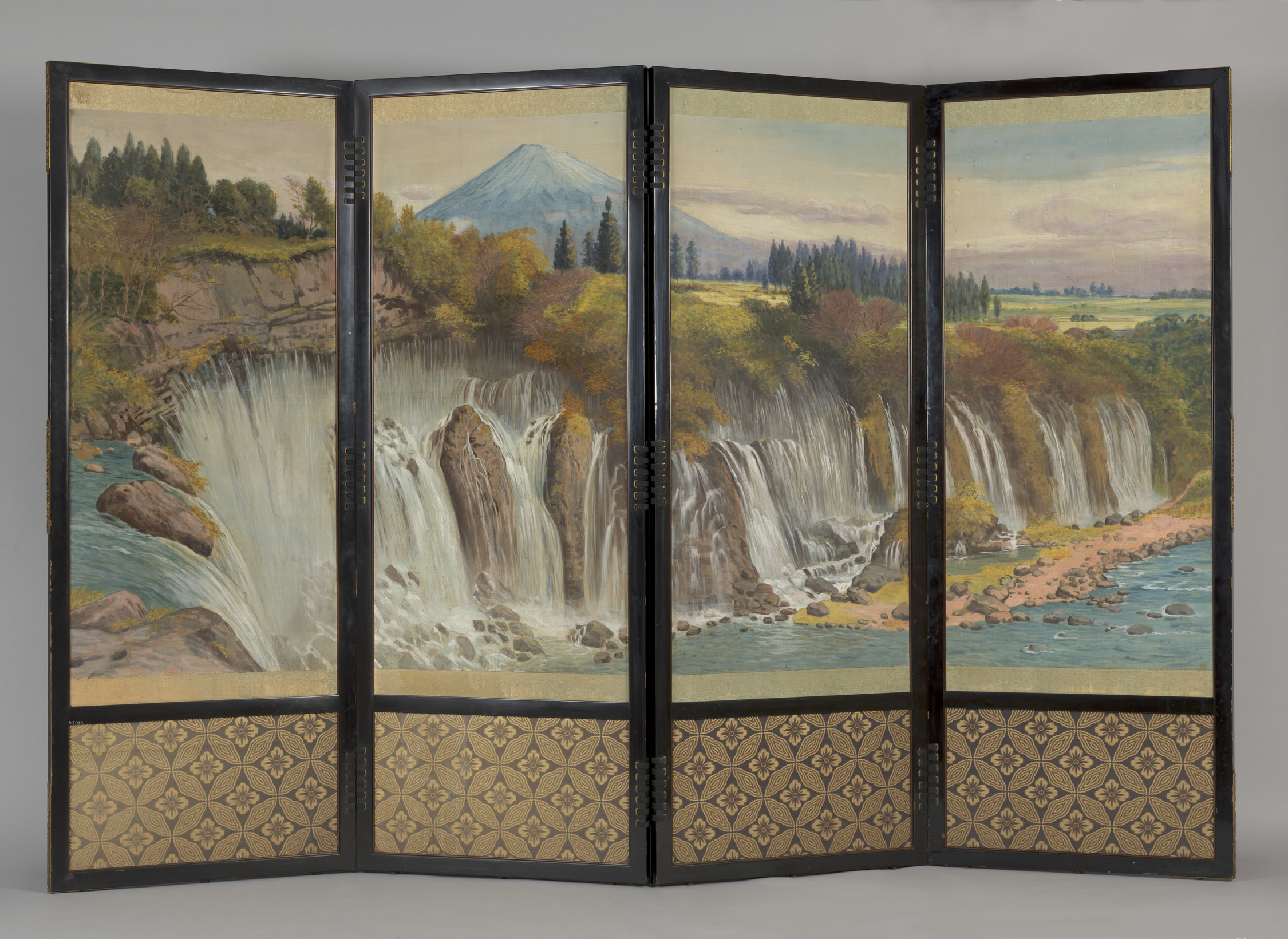 Each of the four panels is fitted with cream silk, which is richly embroidered. The first panel features a pair of cranes standing on rocks and grass, with a pheasant underneath tree peony and cherry-blossom branches. The glossy feathers of the cranes are