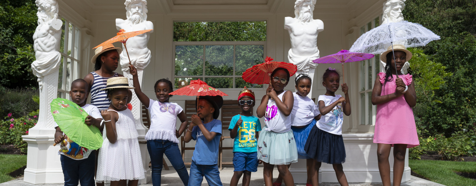 Group of 10 children with parasols in Buckingham Palace gardens