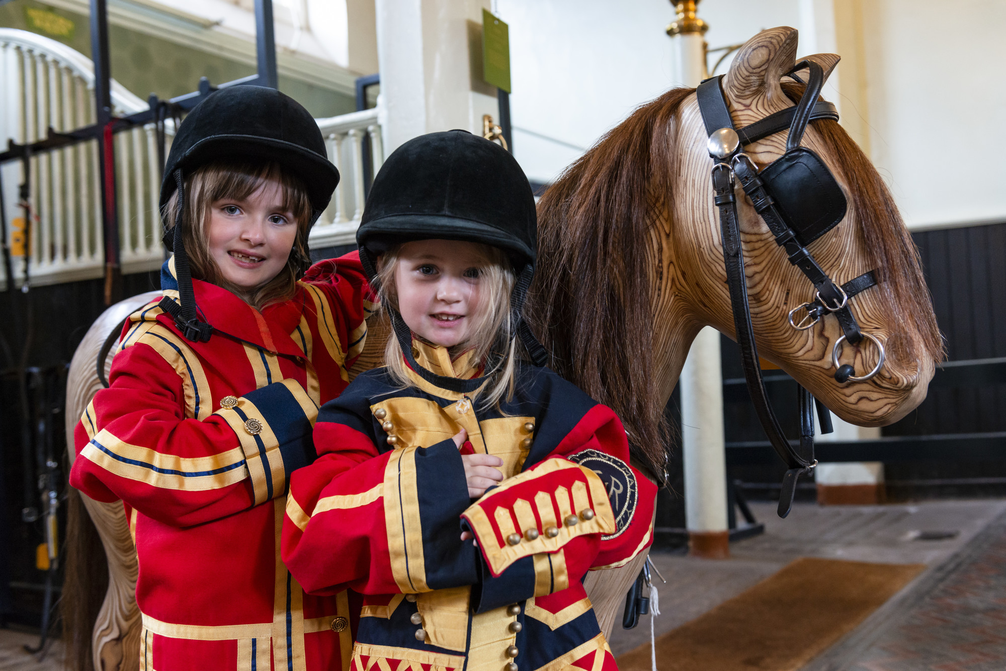 Children dressing up next to a wooden horse