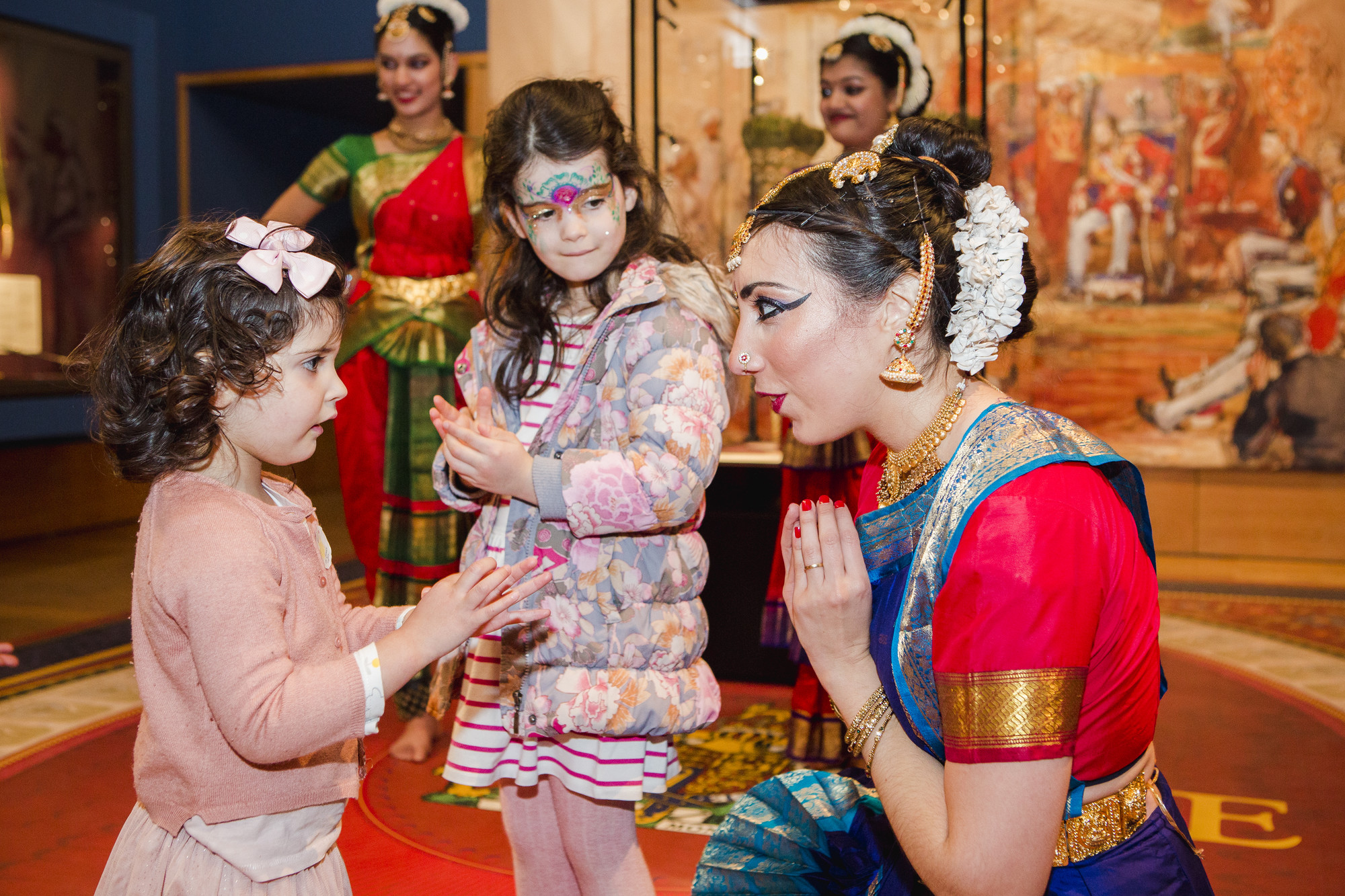 Children taking part in a dance lesson with a lady in traditional Indian dress