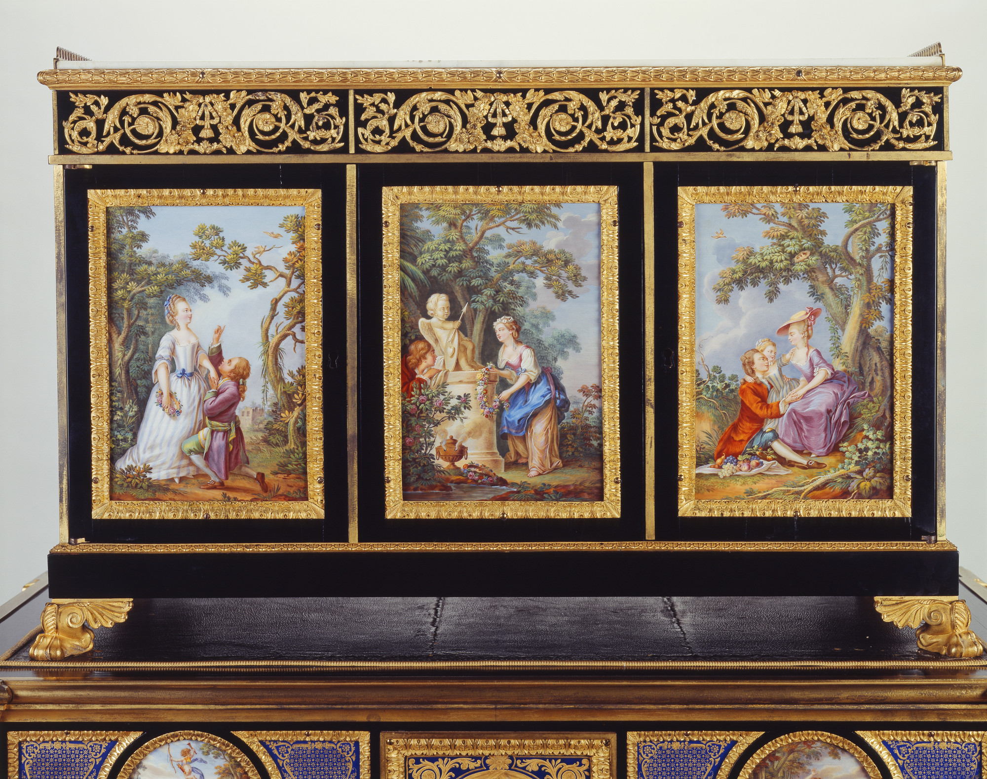 Rectangular porcelain-mounted cabinet on a similarly decorated table, inset with nineteen plaques, each with gilt metal border; cabinet with white marble top with pierced gilt metal gallery; on plinth base with gilt paw feet. Table with four fluted legs, 