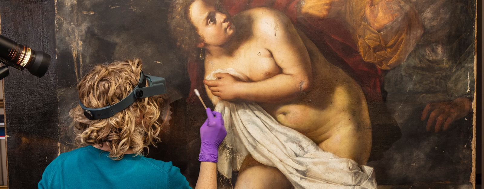 A conservator works on Susanna and the Elders