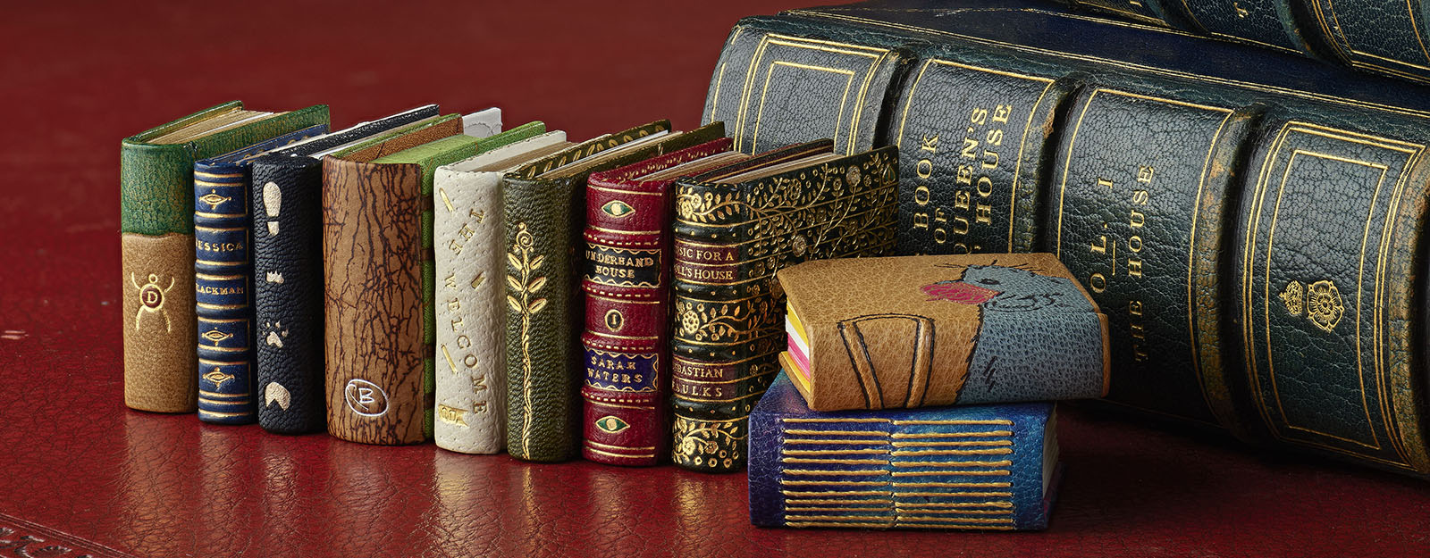 A selection of miniature books lined up next to regular sized book.