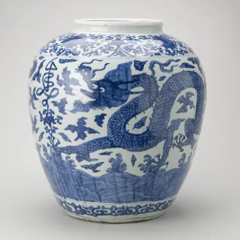 An ovoid-shaped Chinese Ming period porcelain jar painted in rich blue around the sides with two five-clawed dragons among clouds and with rocks and waves below. Round the shoulder a stylised shou (long life character) seems to grow out of the lotus scrol