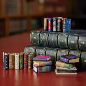 A selection of the new miniature books, with a range of colourful cover designs, shown against the backdrop of the Royal Library at Windsor Castle. 