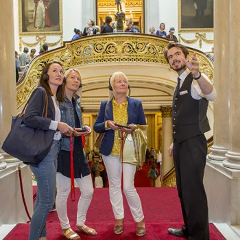 Warden showing three people a room at Buckingham Palace