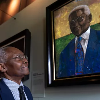 Professor Sir Godfrey (Geoff) Palmer OBE stands next to his portrait painted by Derek Fordjour